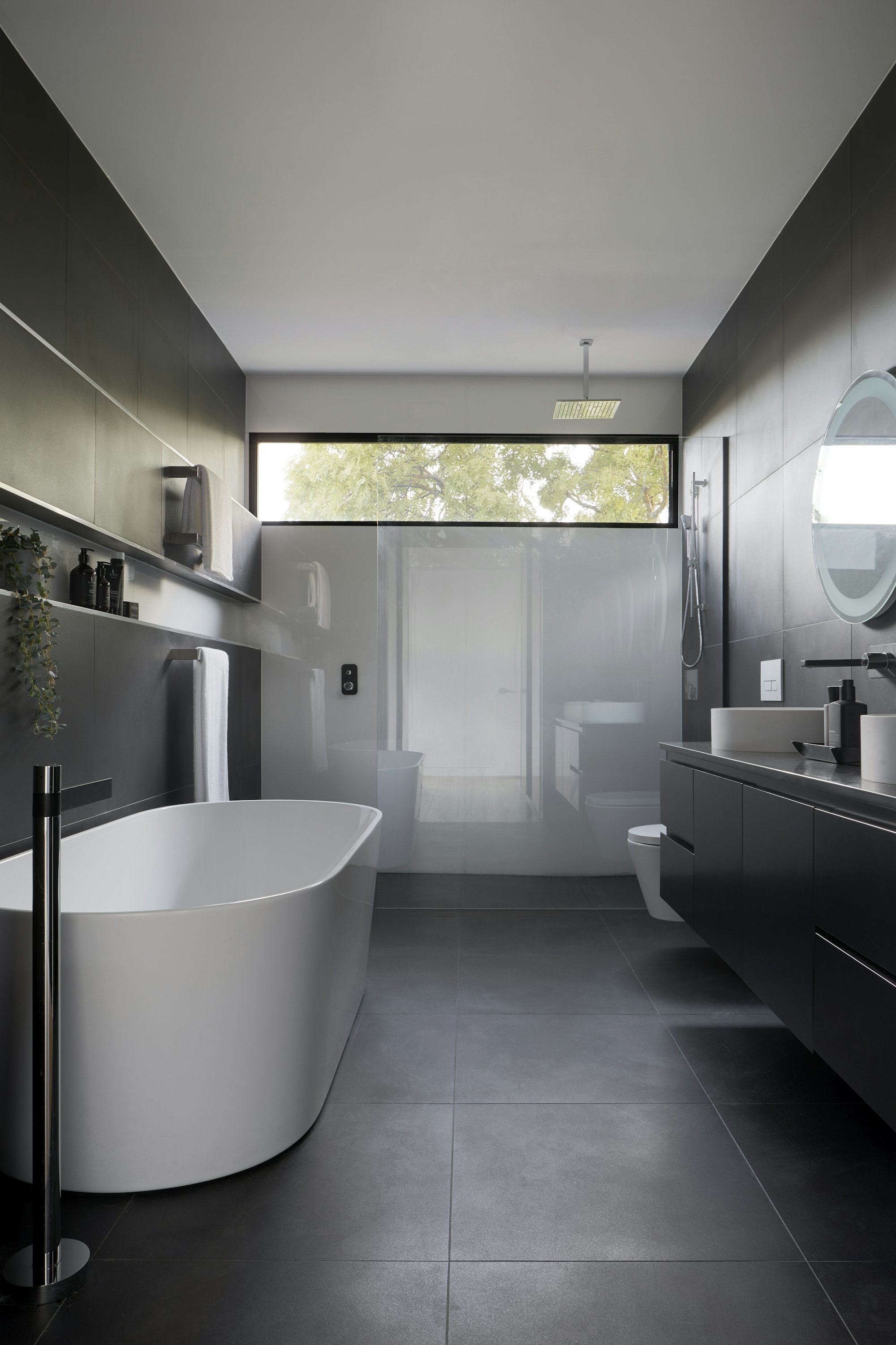A bathroom in dark tile with a freestanding bath