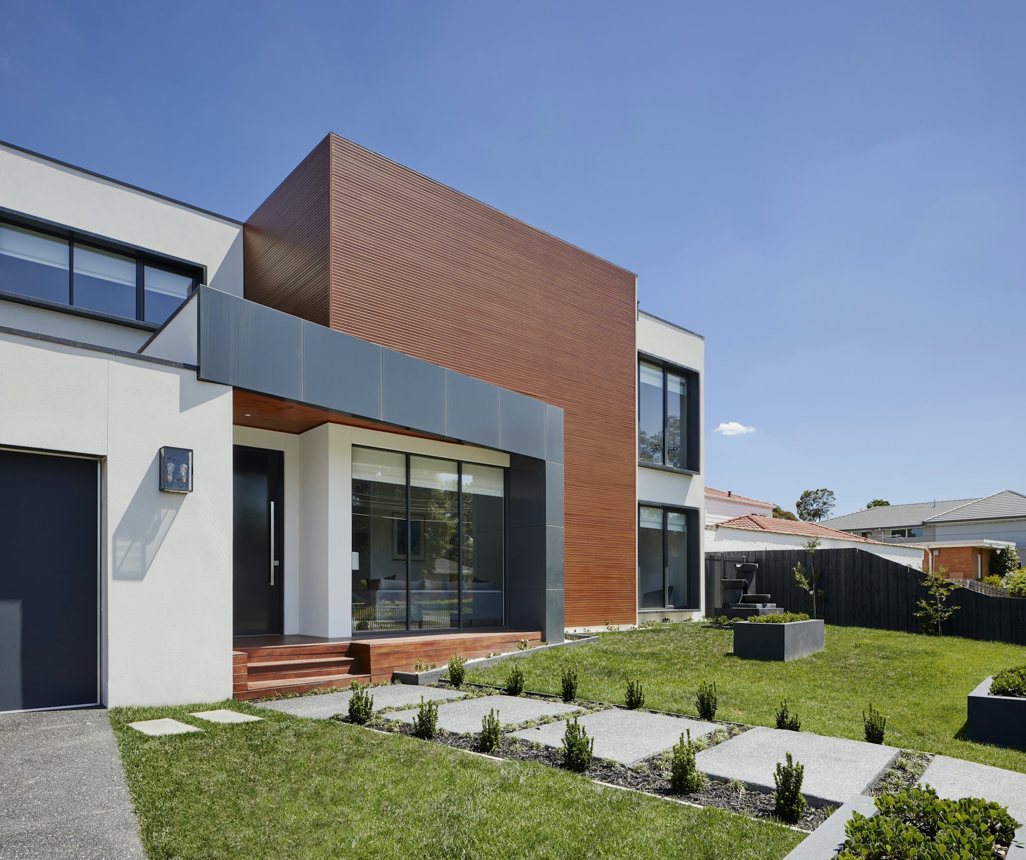 A timber-clad contemporary house seen across a lawn